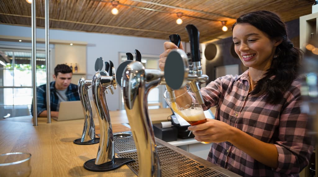 A barmaid is pouring beer.