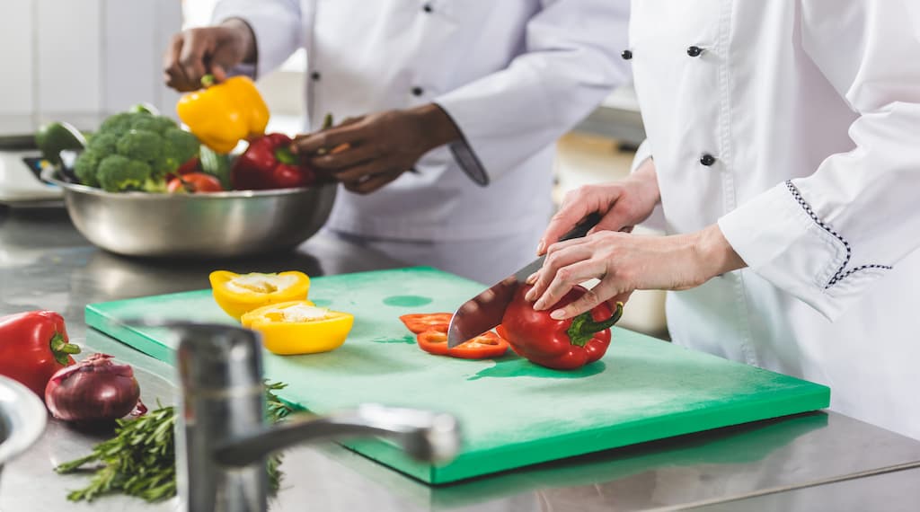 Chef cutting peppers-on-prep-table-cutting-board