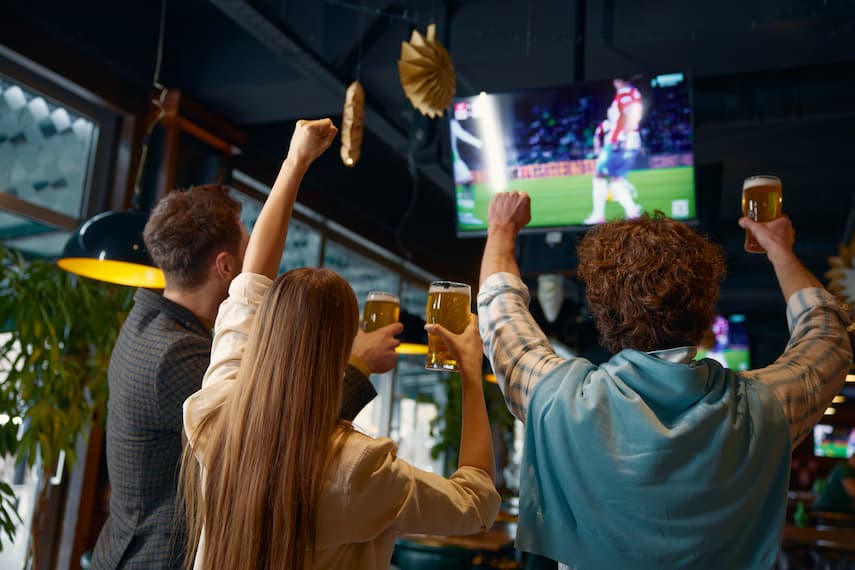 Group of friends watching football drinking beverages.